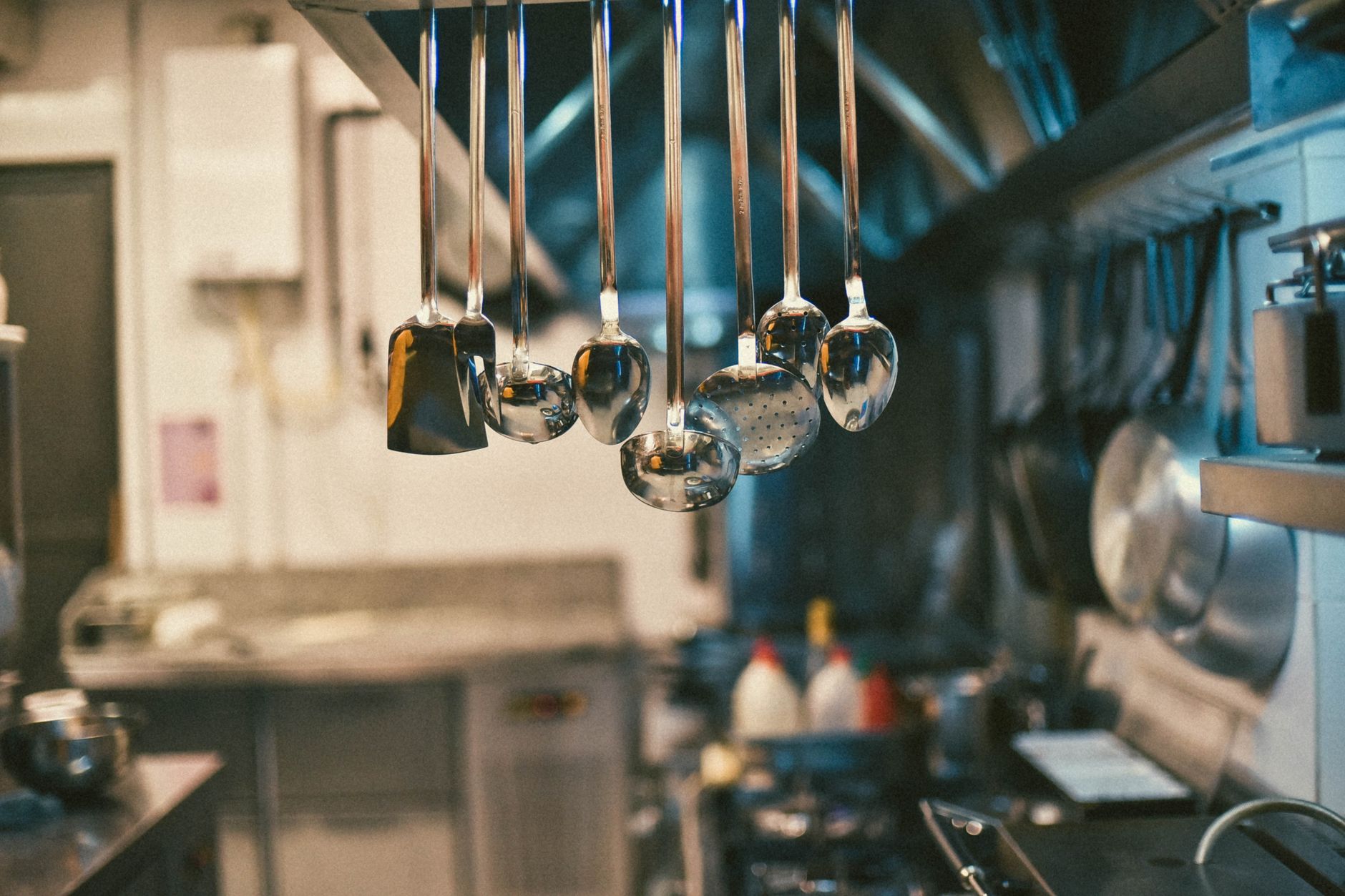 Stainless steel utensils hang in a professional kitchen.